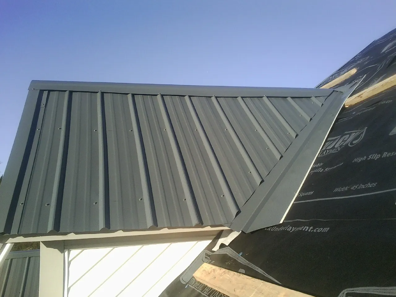 Gray metal roof panels going on over a garage gable in Mc Knightstown