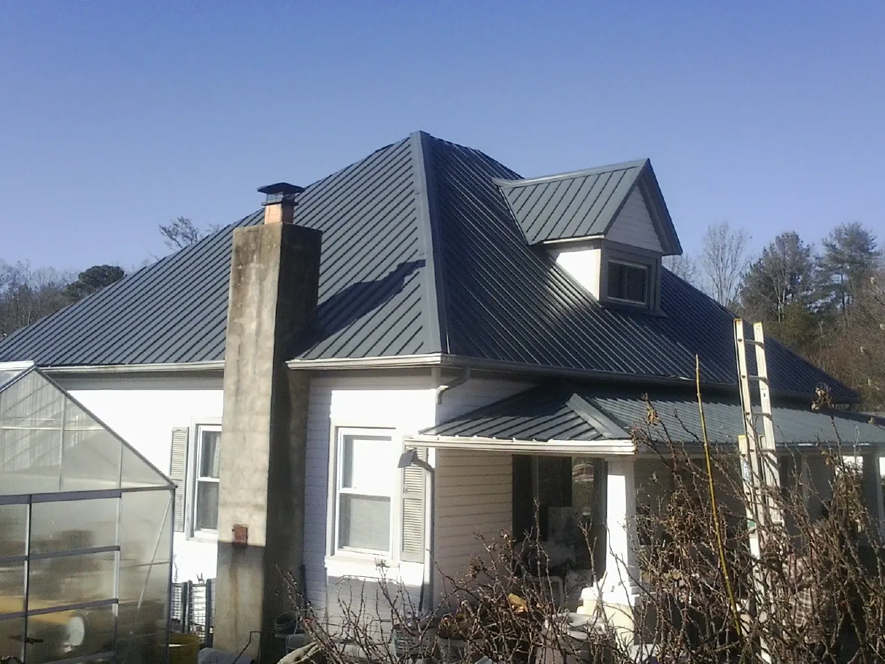Dark blue standing seam metal roof on a white farmhouse with dormer — Slate & Tile Roof Repair by Roofing Brothers in Mc Knightstown