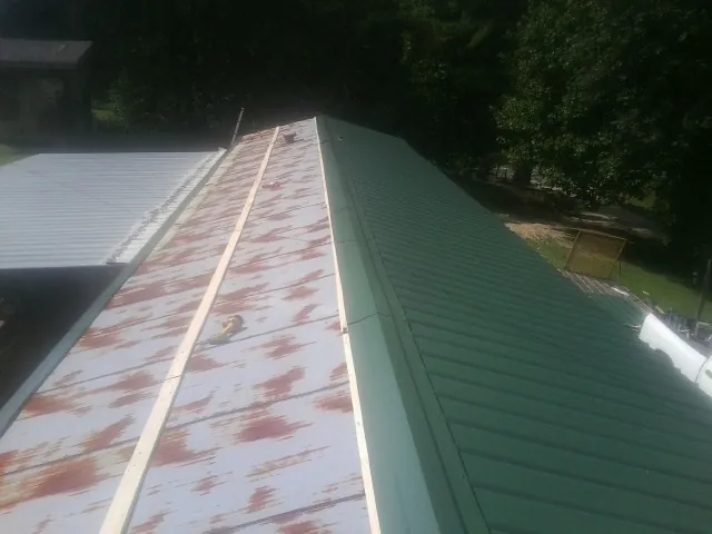 Old rusted panels beside newly installed green metal roofing — Wind Damage Roof Repair by Roofing Brothers in Mc Knightstown