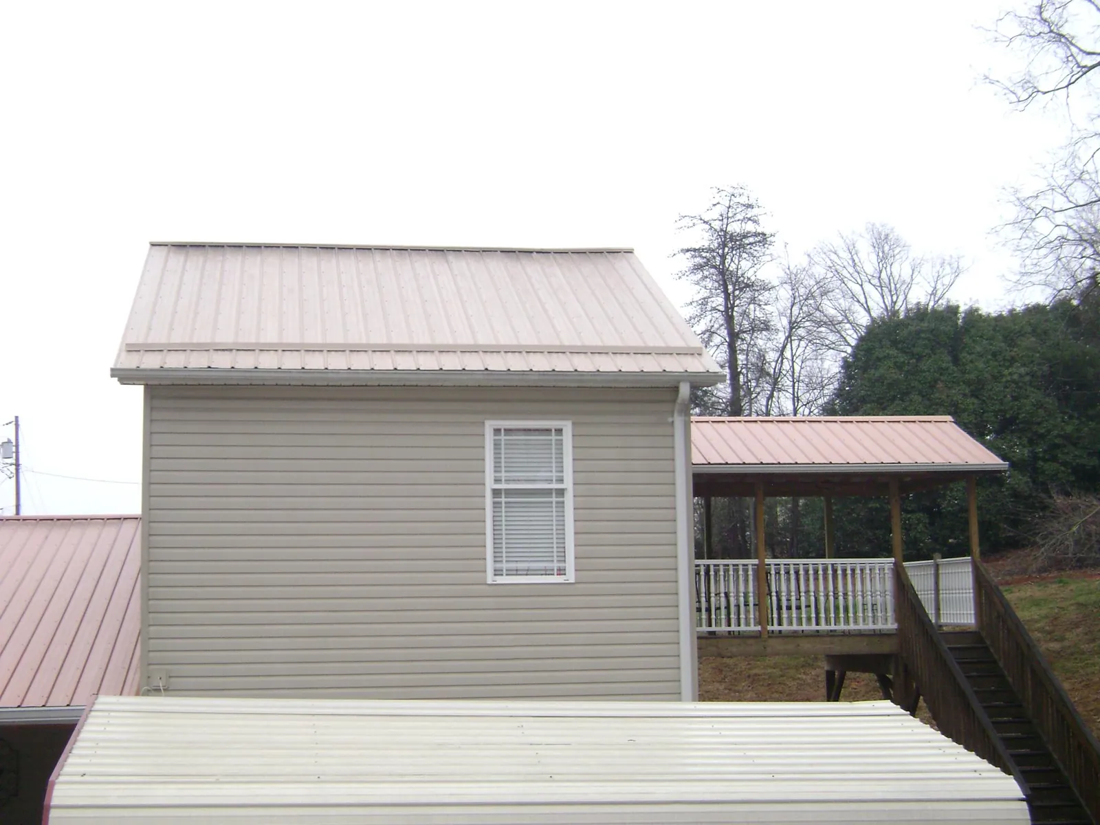 Tan metal roofs on a two story addition and attached porch, from a Roof Replacement job in Mc Knightstown