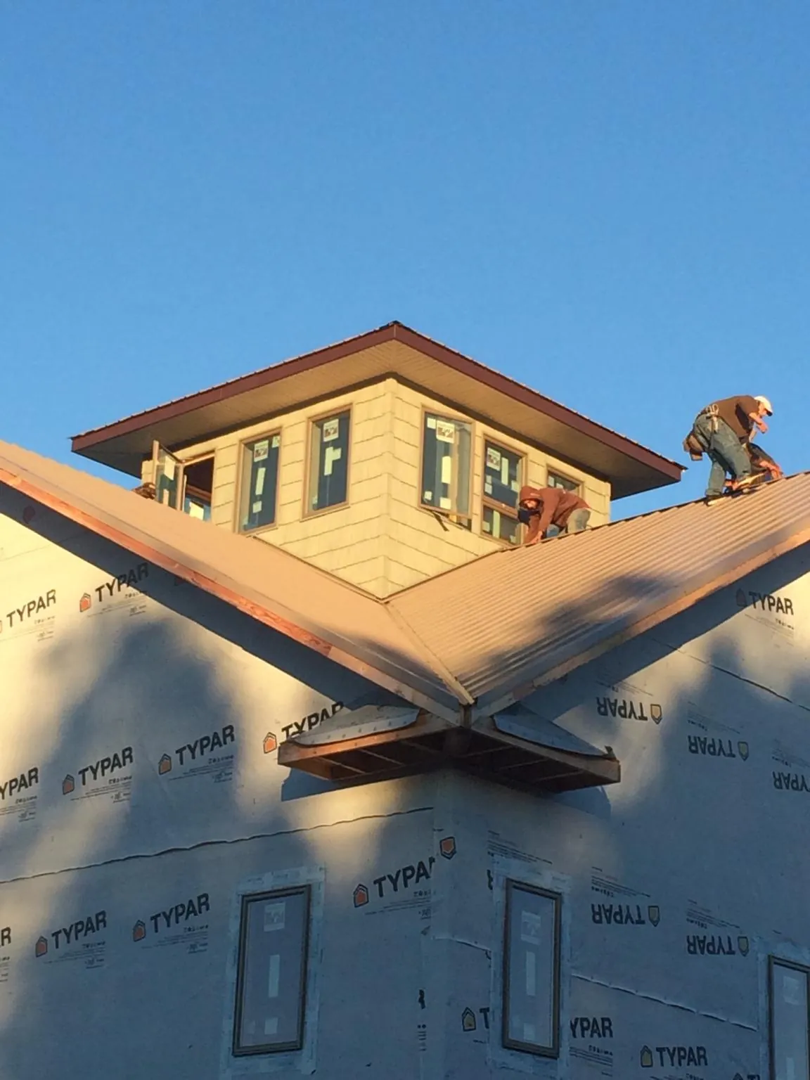 Roofers working around a rooftop cupola on a new metal roof at sunset — Roof Waterproofing in Mc Knightstown by Roofing Brothers
